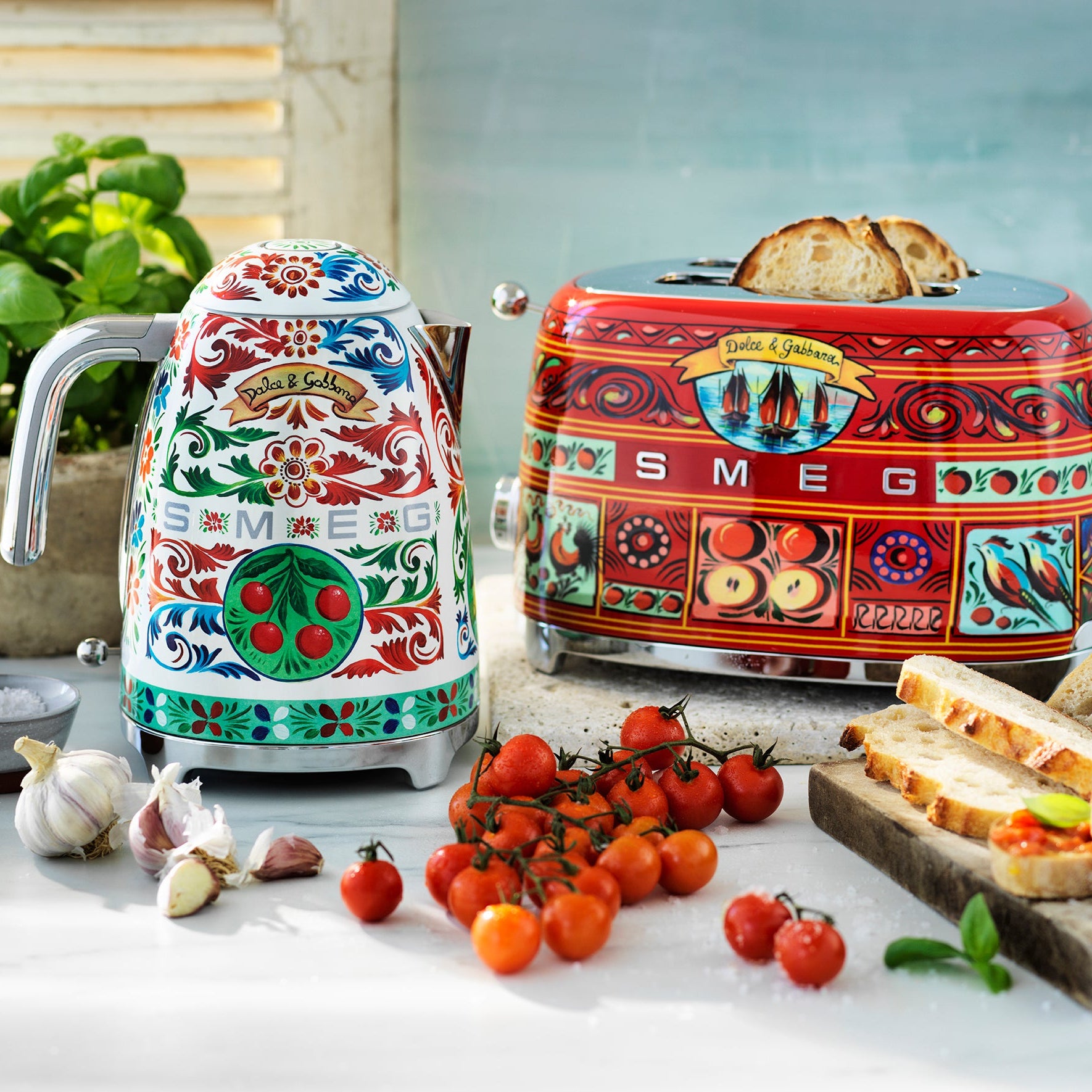 Colorful SMEG kettle and toaster on a kitchen counter with tomatoes and bread.